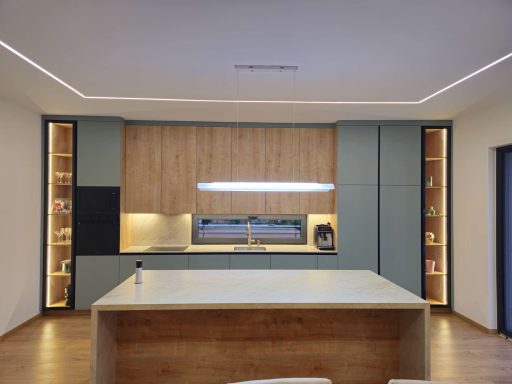 Urbanes Design & warme Kontraste Moderne Küche mit Holz- und grünen Elementen, zentraler Kücheninsel und Beleuchtung.